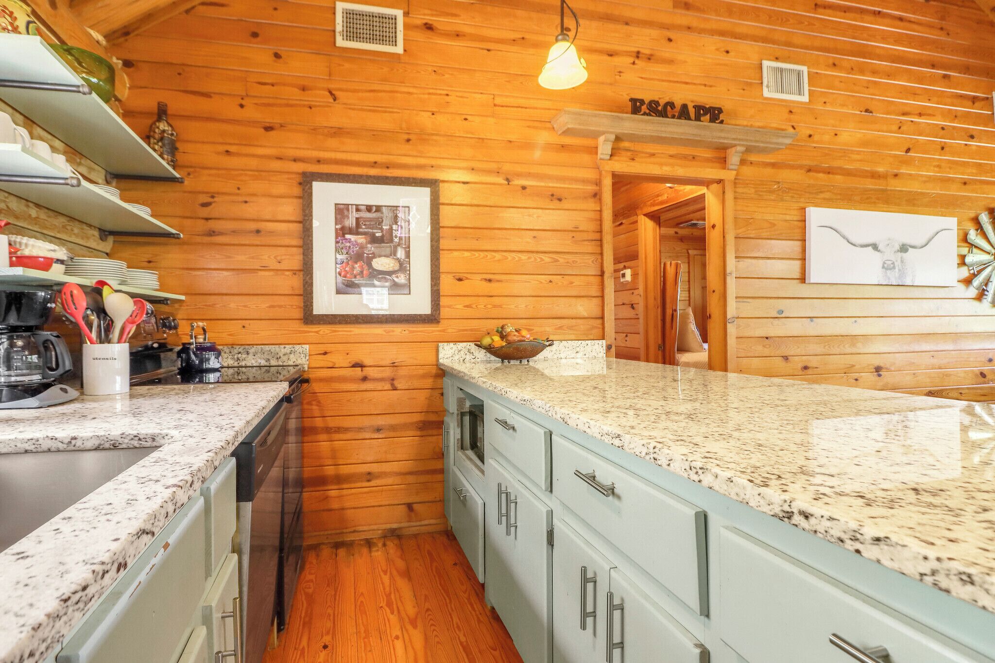 A kitchen with wooden walls, granite countertops, and a framed picture on the wall.