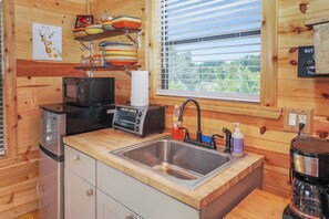 A compact kitchen with a stainless steel sink, a toaster, and a coffee maker. - Safari Treehouse w/ Fire Pit, Grill & Seasonal Creek Views in Dripping Springs (Wimberley)
