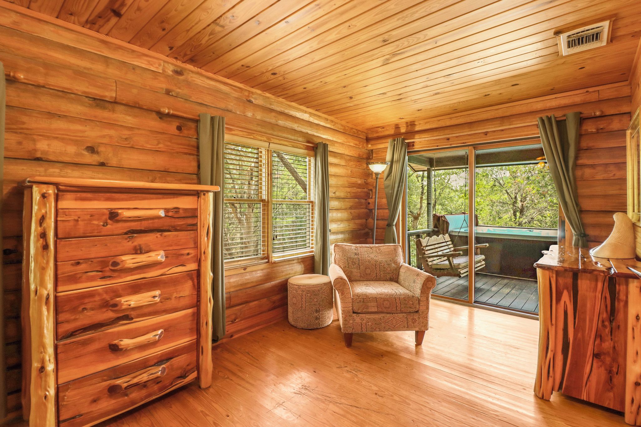 A wooden cabin interior with a sofa, ottoman, and a wooden cabinet.