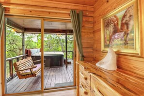 Una cabaña de madera con un porche, una banca, un jacuzzi y un cuadro de un caballo.