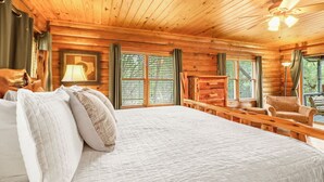 Un dormitorio tipo cabaña con una cama grande, una chimenea y vistas al exterior.