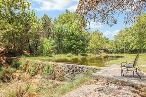 A stone bench by a calm pond surrounded by lush greenery. - Popular 2BR Log Home on the Creek with a Hot Tub! (Wimberley)