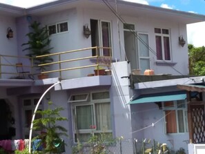 A two-story house with a balcony, a covered porch, and a small garden area.