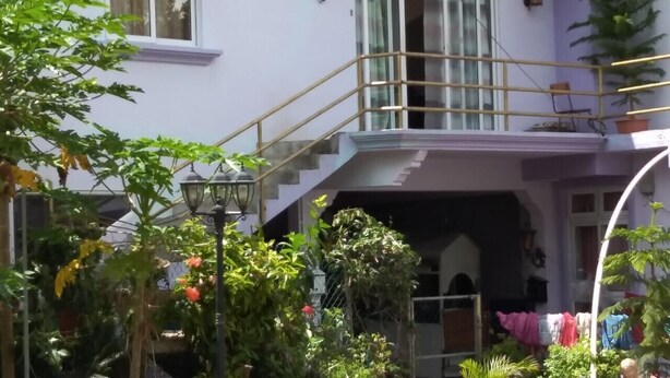 A two-story house with a balcony, a staircase, and a garden with various plants and flowers. - Private House for Rent in Mauritius at a very competitive Price and very secure. (Phoenix)