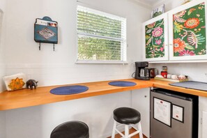 A kitchen with a wooden countertop, a coffee maker, and a refrigerator.