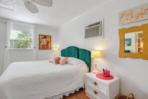 A bedroom with a bed, bedside table, lamp, and a painting on the wall.