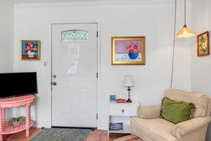 Una sala de estar con televisor, una puerta con ventana, un sofá y adornos en la pared.