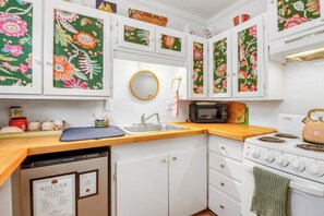 A kitchen with white cabinets, a microwave, a stove, and a sink.