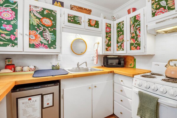 A kitchen with white cabinets, a microwave, a stove, and a sink.