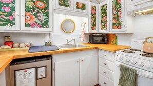 Una cocina con armarios blancos, microondas, estufa y fregadero.