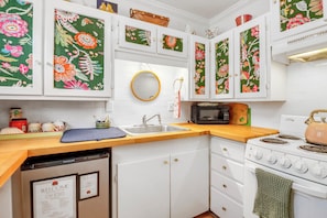 Una cocina con armarios blancos, microondas, estufa y fregadero.