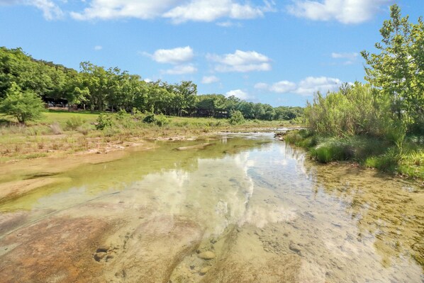 A river with clear water, surrounded by greenery and trees.