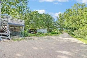 A gravel driveway leading to a covered outdoor area with a staircase and a fenced-in structure. - Cozy and clean loft on the Blanco River - Minutes from downtown Wimberley! (Wimberley)
