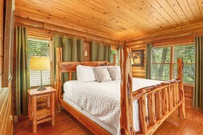Een slaapkamer in een houten chalet met een hemelbed, een nachtkastje en een raam met gordijnen.