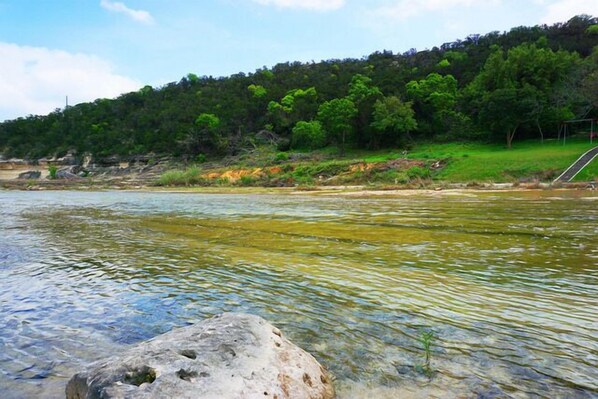 Un río de aguas cristalinas, rodeado por una ladera boscosa.