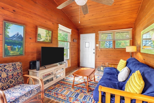 A wooden cabin interior with a television, sofa, and chairs. - Cozy and clean loft on the Blanco River - Minutes from downtown Wimberley! (Wimberley)