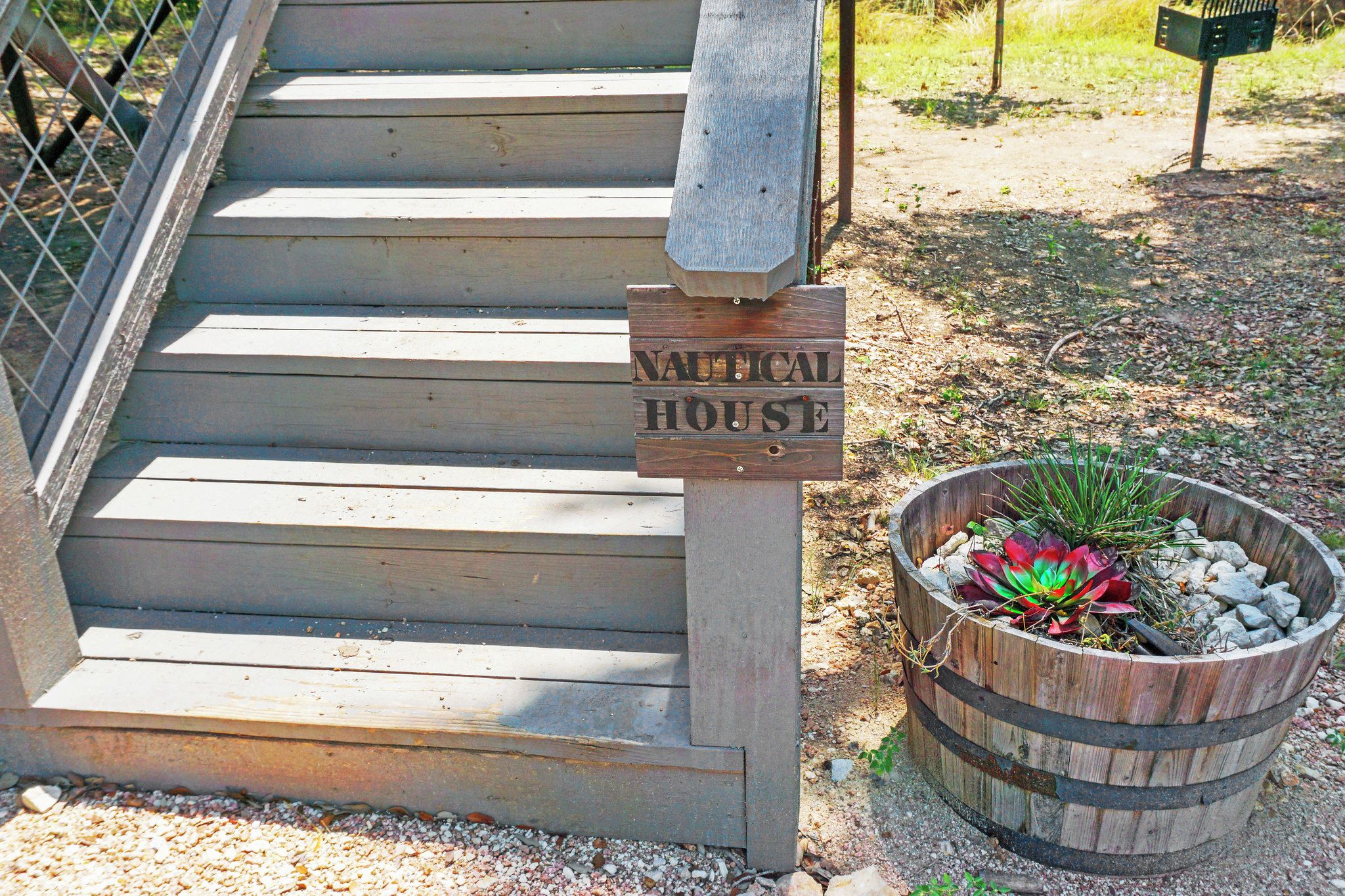 Eine Holztreppe führt zu einem Haus im Seestil, mit einem Schild, auf dem "NAUTICAL HOUSE" steht.