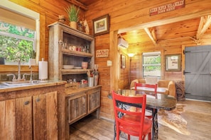 A rustic wooden interior with a kitchen area, dining table, and chairs.