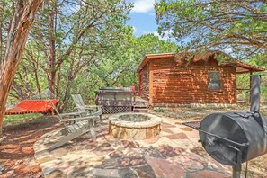 A rustic cabin with a stone fire pit and outdoor seating. - Private, cozy and romantic cabin - a Wimberley favorite! Private hot tub! (Wimberley)