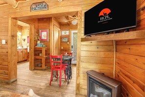 A wooden interior with a television displaying the logo of Hill Country Premier Lodging. - Private, cozy and romantic cabin - a Wimberley favorite! Private hot tub! (Wimberley)