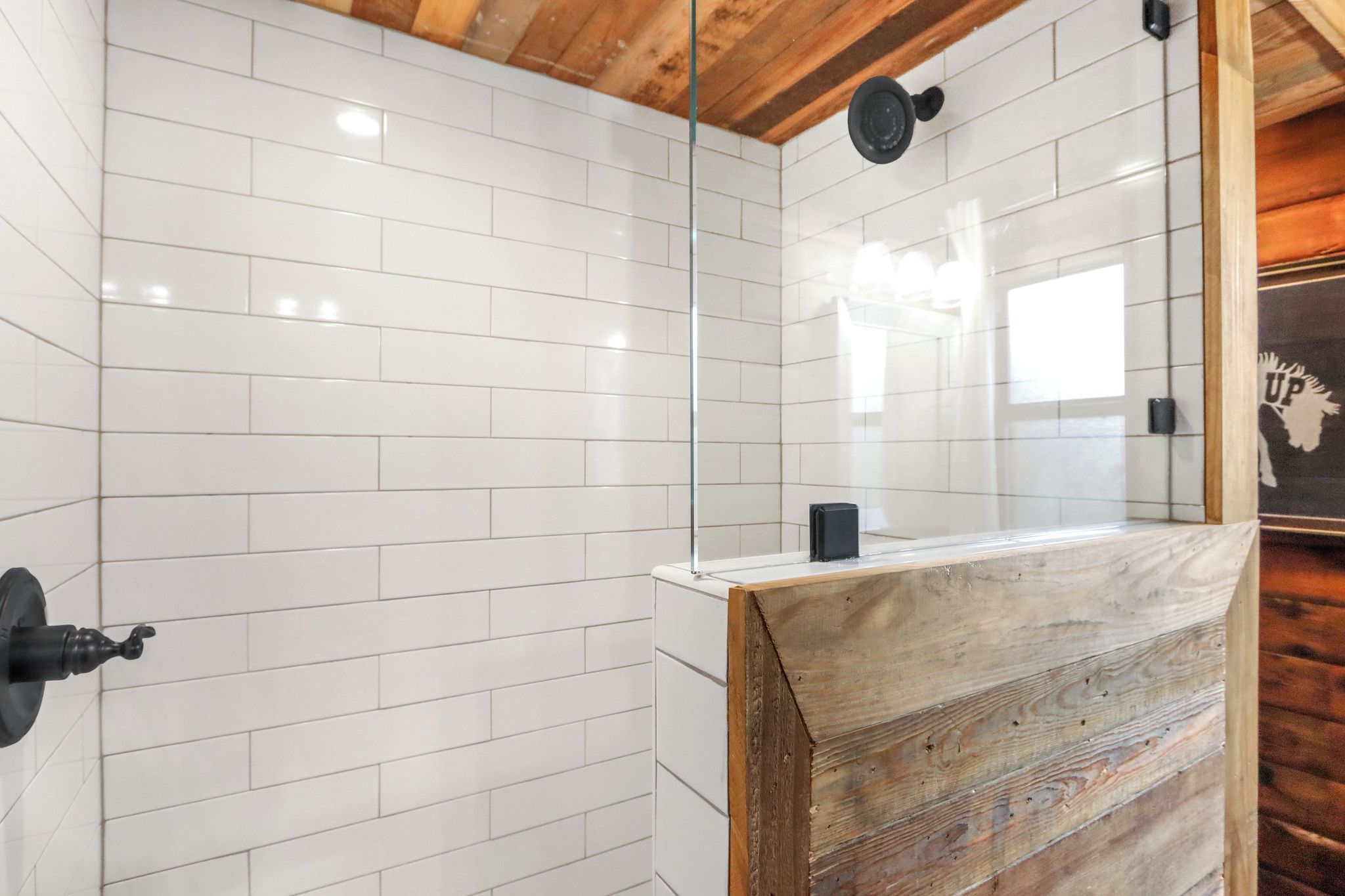 A bathroom with white tiled walls, a wooden bench, and a mirror.