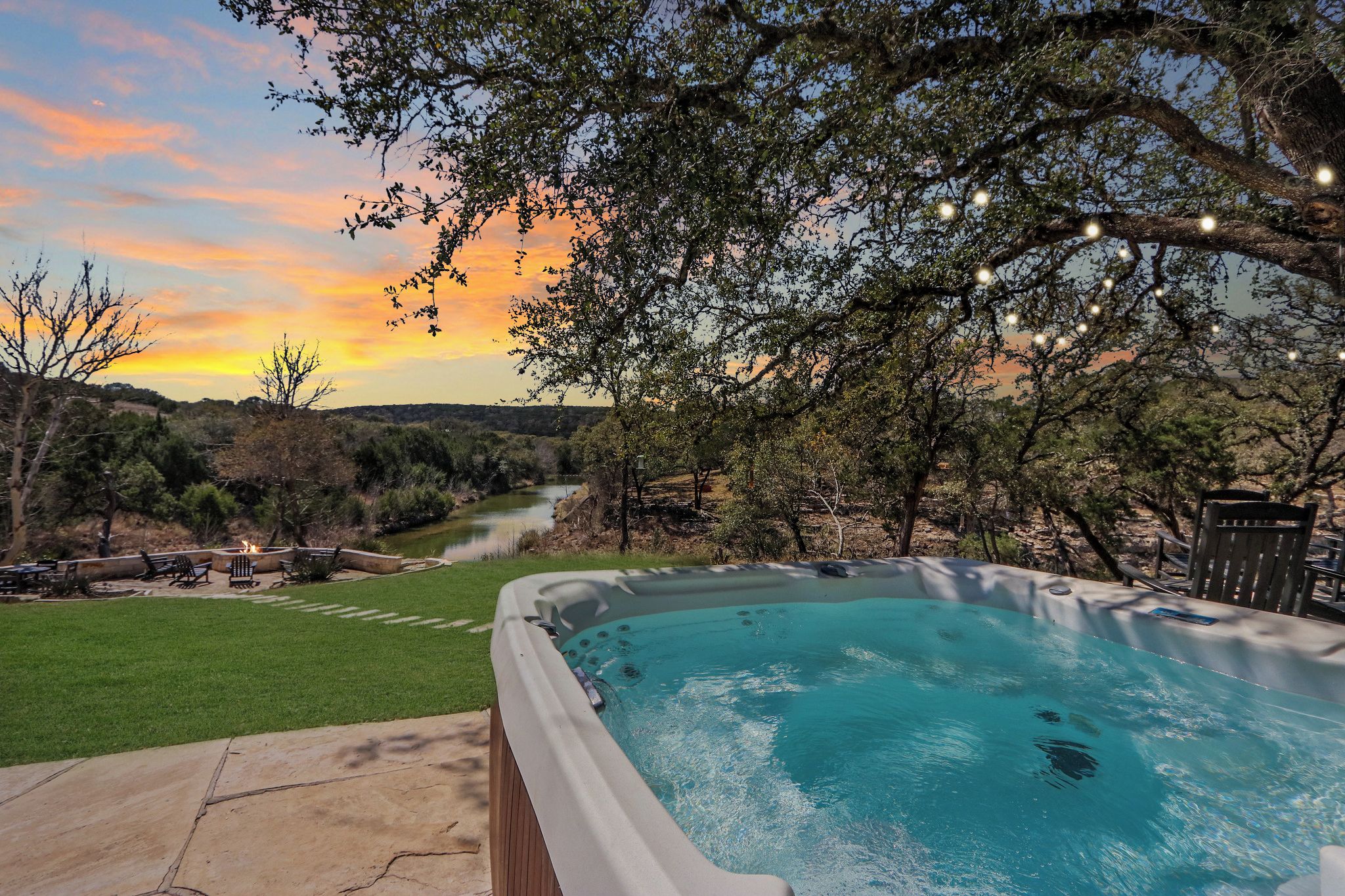 Un jacuzzi con vistas a un río y árboles al atardecer.