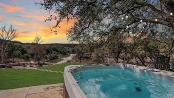 Un jacuzzi con vistas a un río y árboles al atardecer.