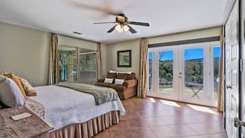 Un dormitorio con cama, ventilador de techo, puerta corrediza al patio y vistas al exterior.