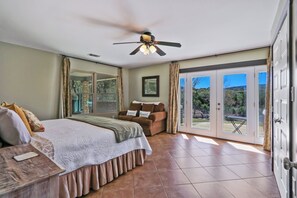 Un dormitorio con cama, ventilador de techo, puerta corrediza al patio y vistas al exterior.