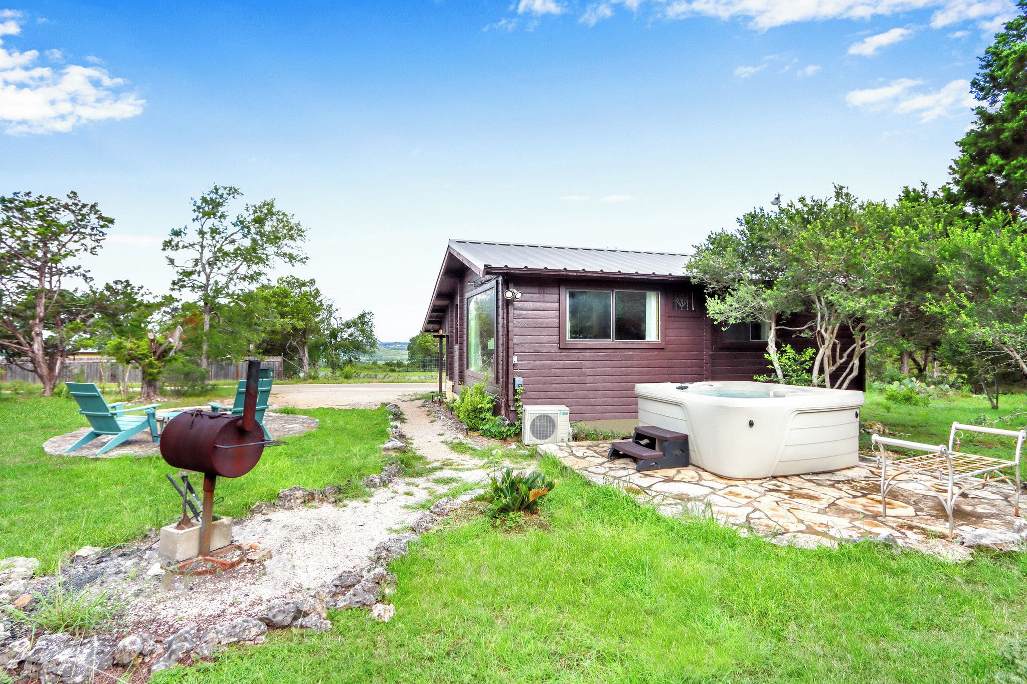 A rustic cabin with a hot tub and a barbecue grill in the yard.