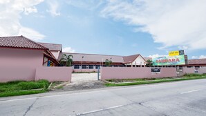 Un hotel con un tetto in tegole rosse e un grande cartello pubblicitario che mostra il nome dell'hotel e i prezzi.
