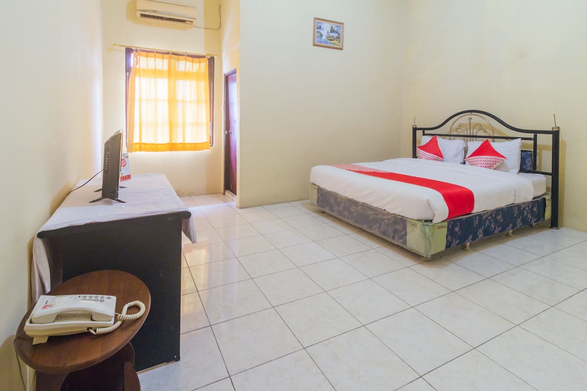 Une chambre d’hôtel avec un lit, un bureau avec un téléphone et une fenêtre avec des rideaux.