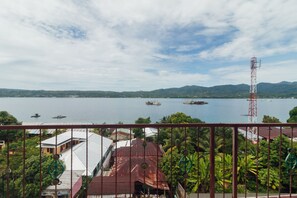 A coastal view with boats on the water, a red communication tower, and buildings with red roofs. - Hotel O Astika (Ambon)
