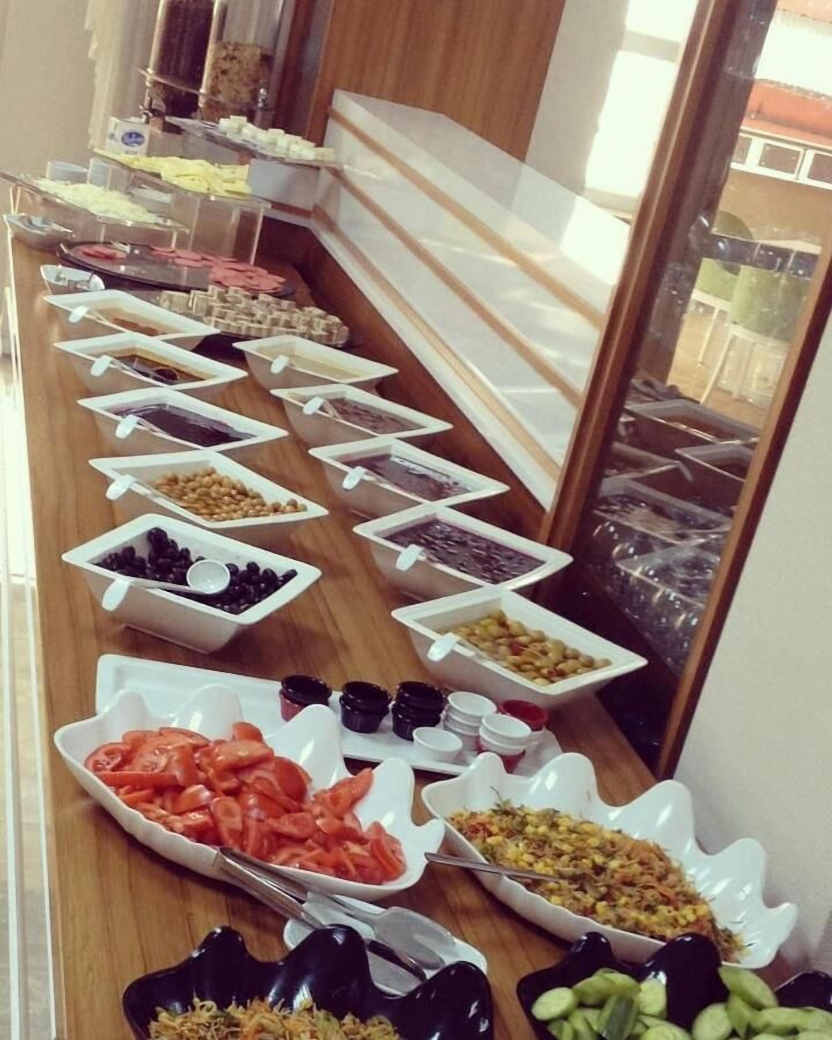 A buffet with various food items arranged in white bowls and trays.