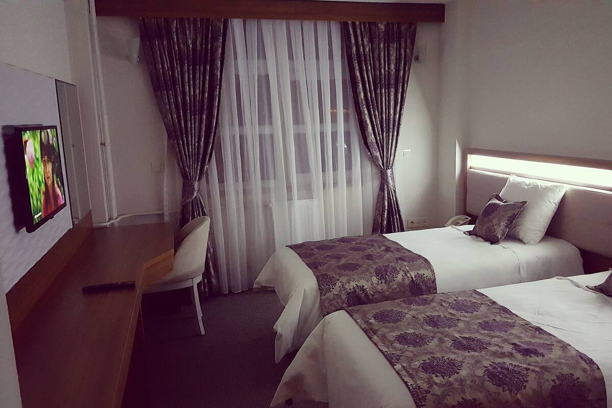 Ein Hotelzimmer mit zwei Betten, einem Schreibtisch und einem Stuhl.