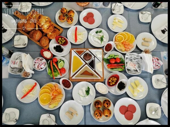Una mesa servida con varios platos que incluyen pan, pasteles, frutas, verduras y condimentos.