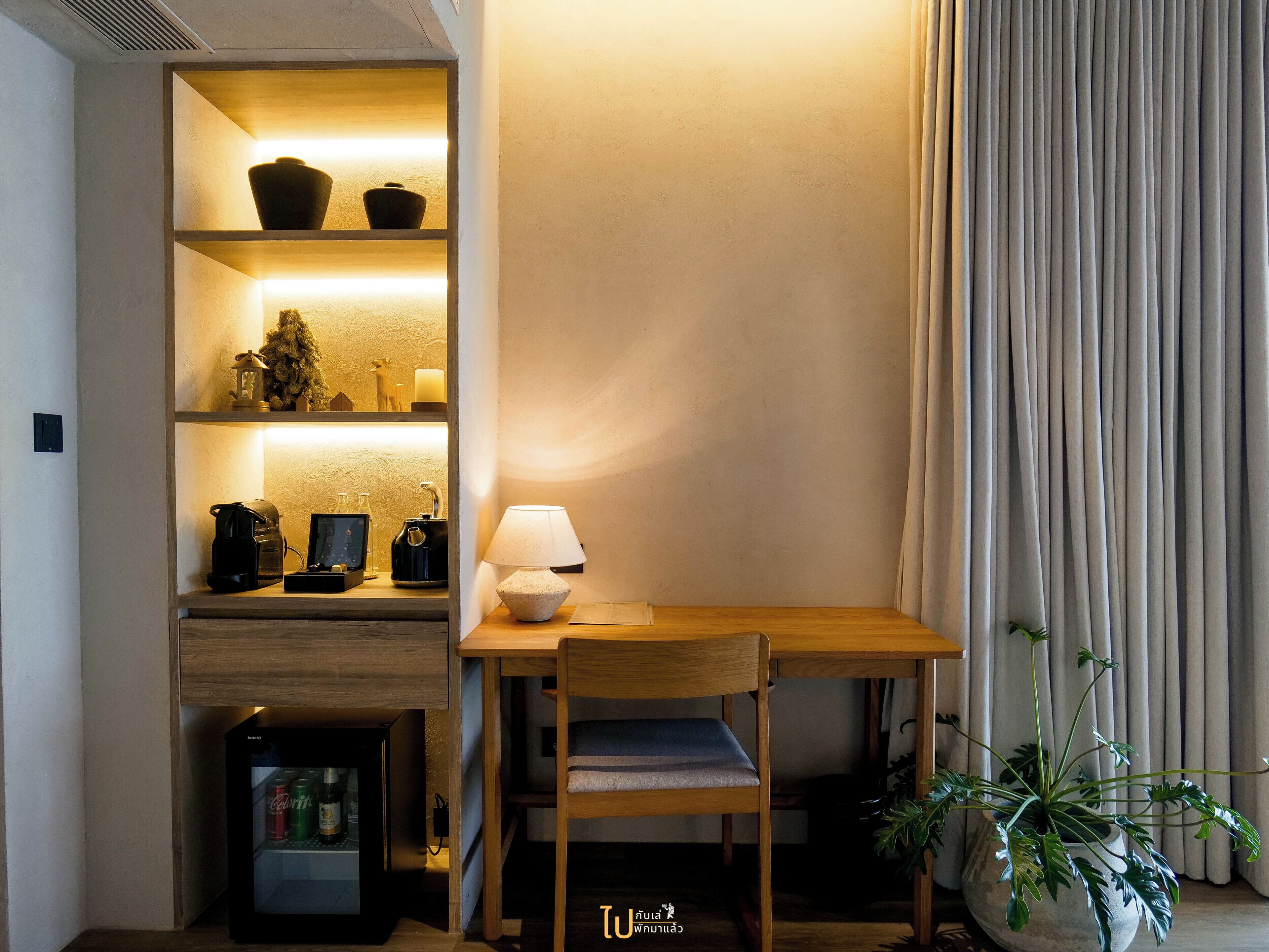 A cozy corner with a wooden table, a chair, a lamp, and a shelf with various items including a small plant.