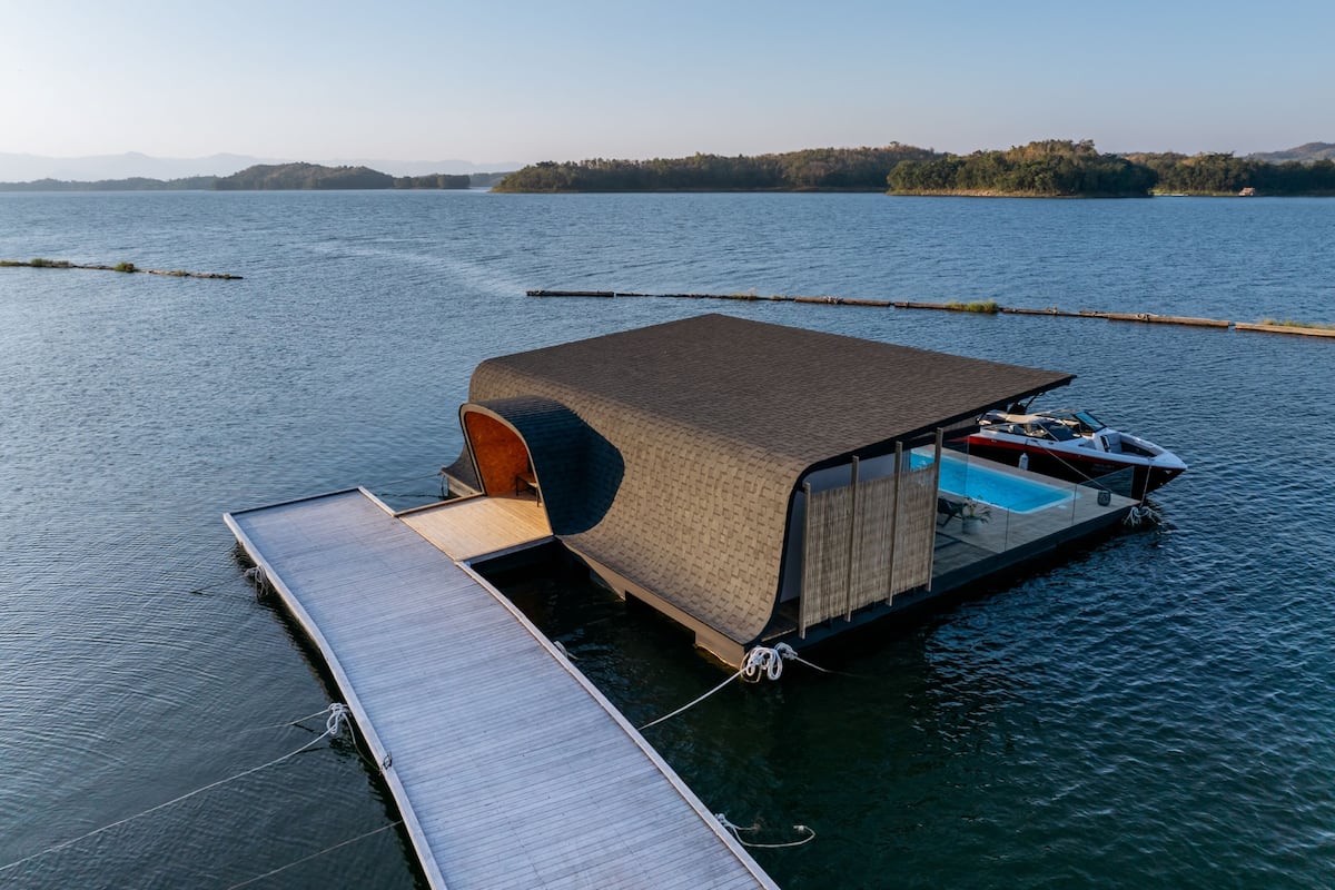 A floating house with a covered swimming area and a dock.