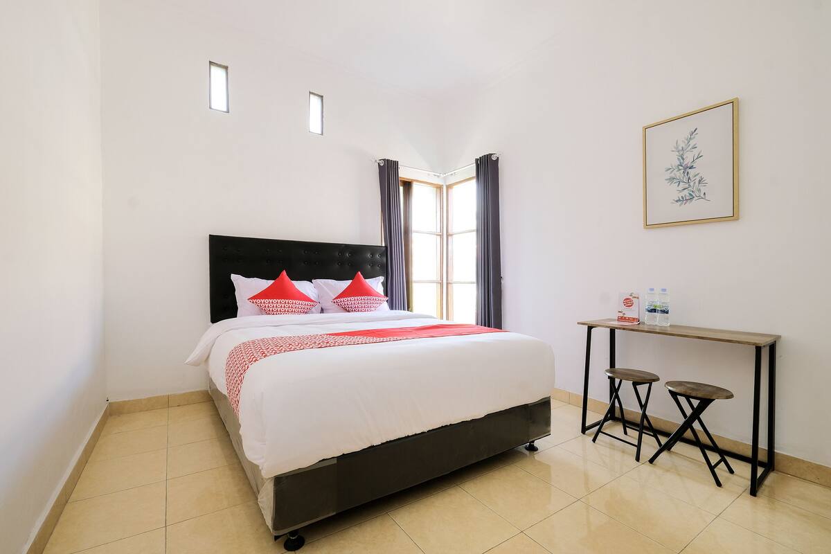 A neatly arranged bedroom with a bed, a small table, and a chair.