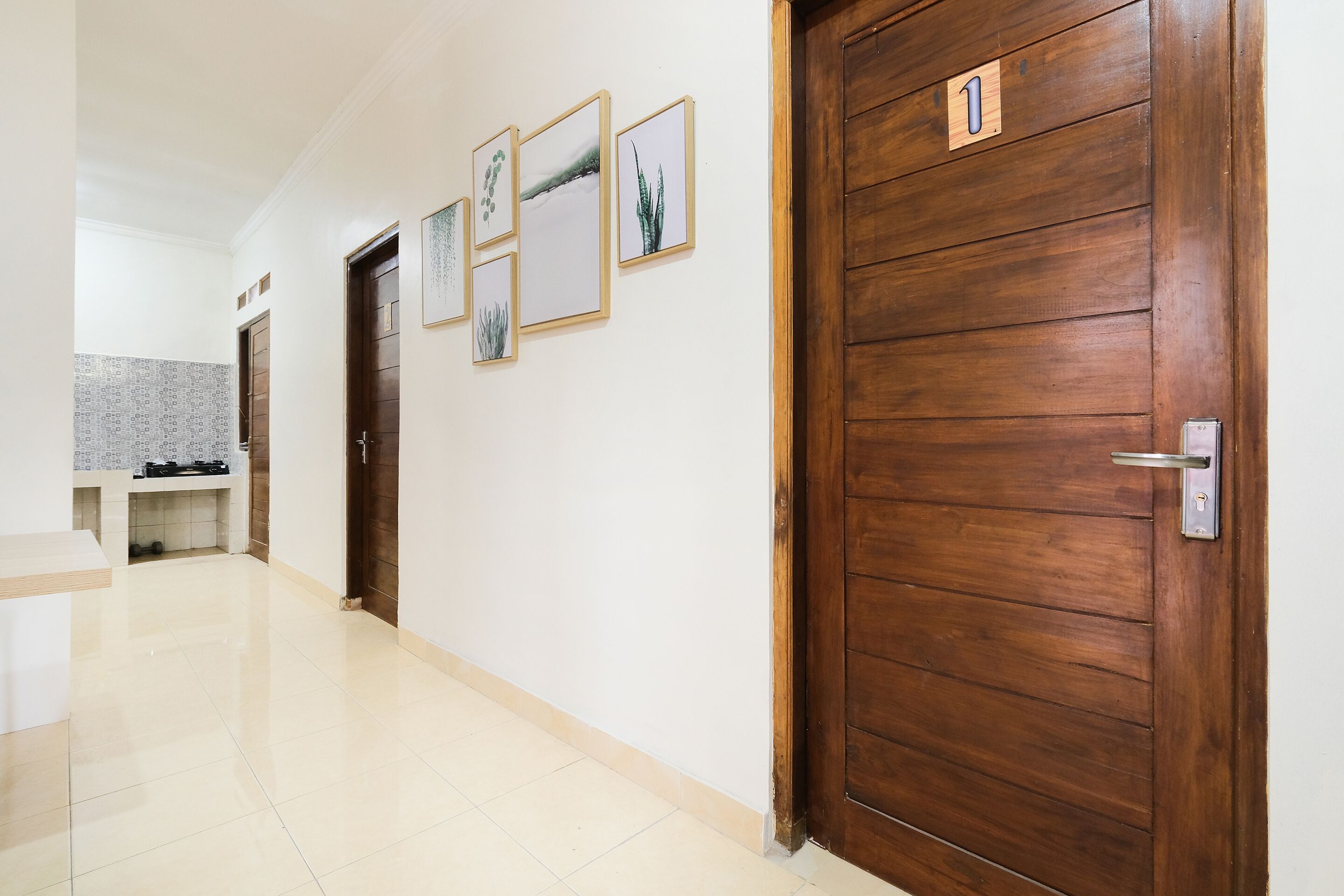Um corredor com portas de madeira, uma área de cozinha e quadros nas paredes.