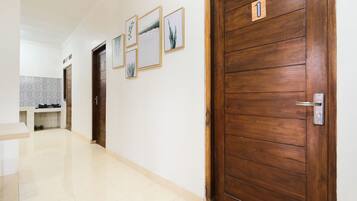 Um corredor com portas de madeira, uma área de cozinha e quadros nas paredes.