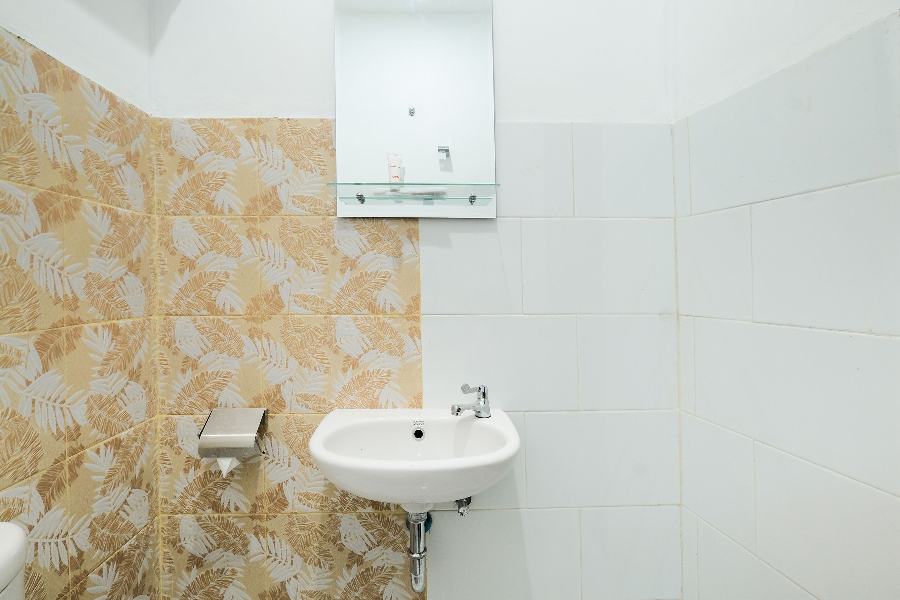 Ein Badezimmer mit einem weißen Waschbecken, einem Spiegel darüber und gemusterten Fliesen an den Wänden.
