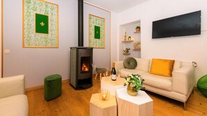 A living room with a fireplace, a sofa, a coffee table, and a flat-screen TV mounted on the wall. - Zythogite Appartement 9 personnes (Tintigny)