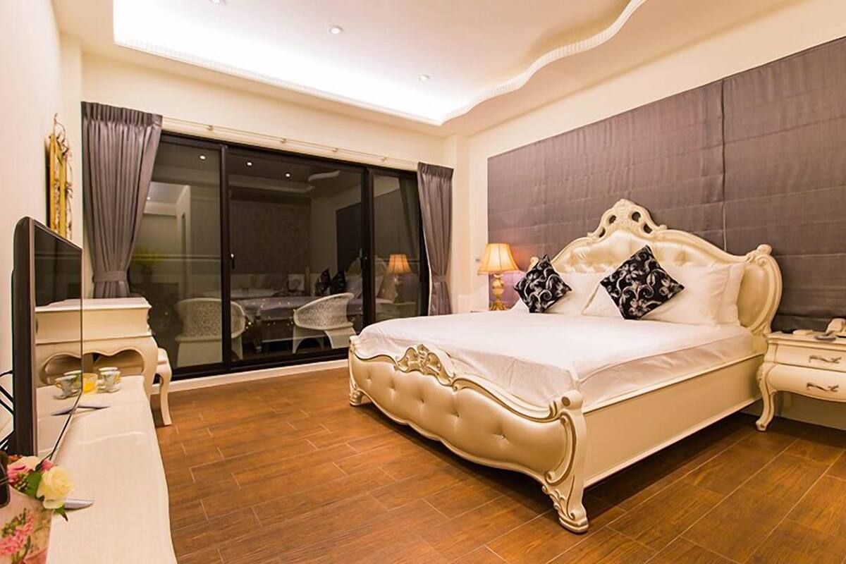 Un dormitorio espacioso con una cama grande, televisor y un área de comedor con sillas.
