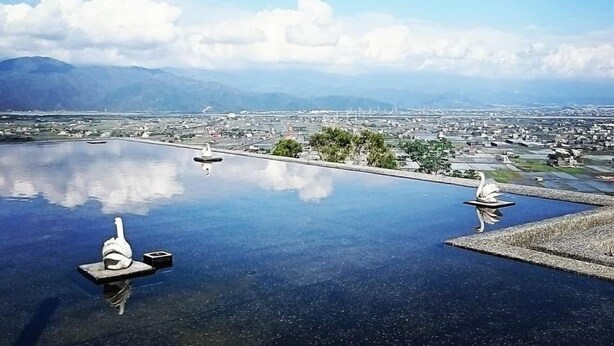 A rooftop pool with two swan statues and a cityscape view in the background. - Moonstone Bed and Breakfast (Sanxing)
