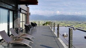 A balcony with lounge chairs, a view of a valley, and mountains in the distance. - Moonstone Bed and Breakfast (Sanxing)