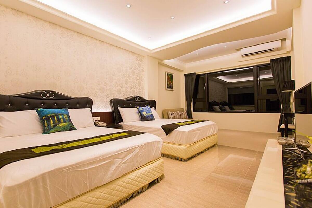 Habitación de hotel con dos camas, un escritorio y un ventanal grande.