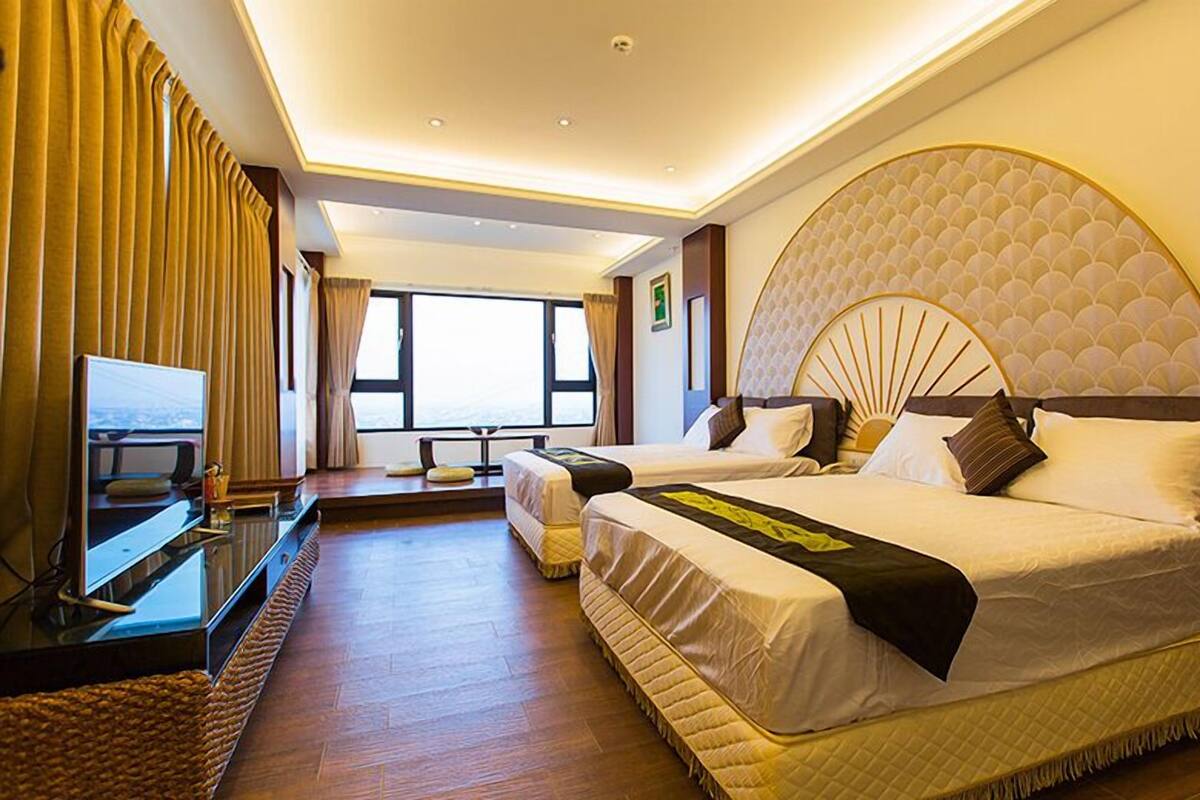 Habitación de hotel con dos camas, un televisor y un ventanal con vistas.