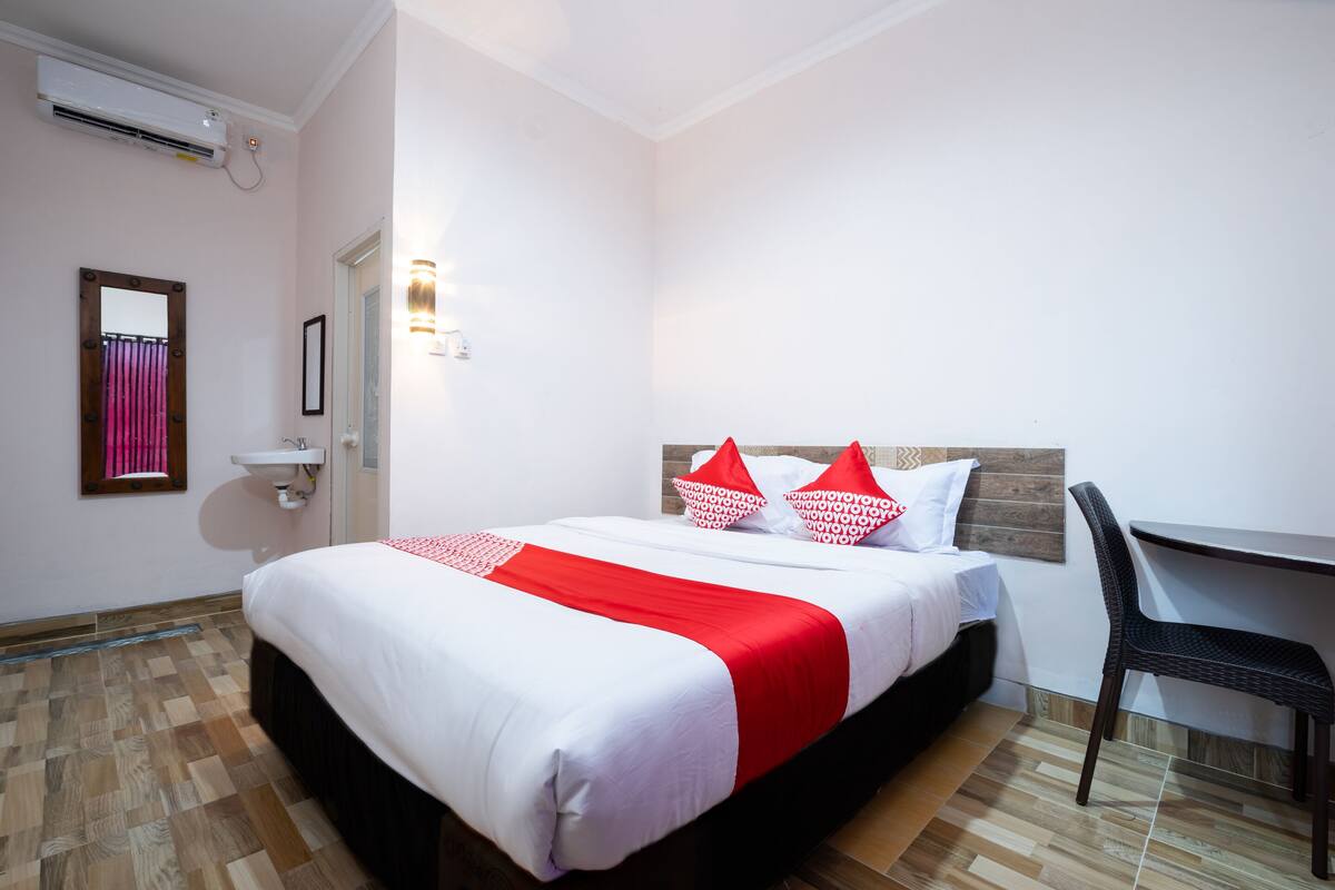 A hotel room with a bed, a desk, and a chair.