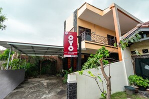 A two-story building with a sign for "OYO Art Guesthouse Syariah" and a covered outdoor area with potted plants. - Hotel O Art Guest House Syariah (Yogyakarta)